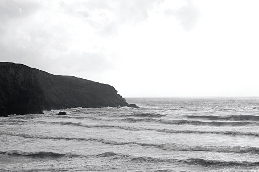 Stormy waters lap the bottom of the cliff on a blustery day in...